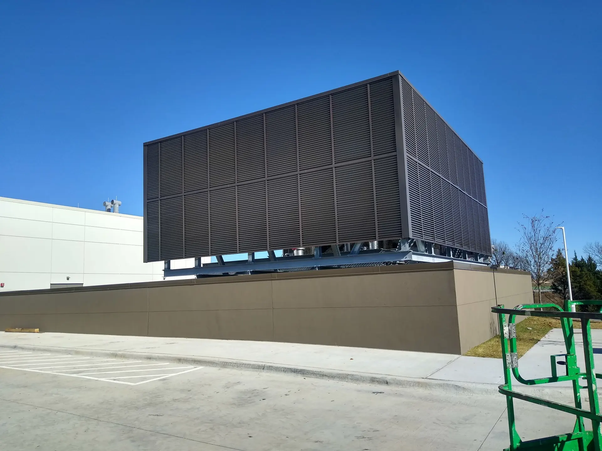 Louvered rooftop equipment screen sized to keep free area at HVAC air intakes