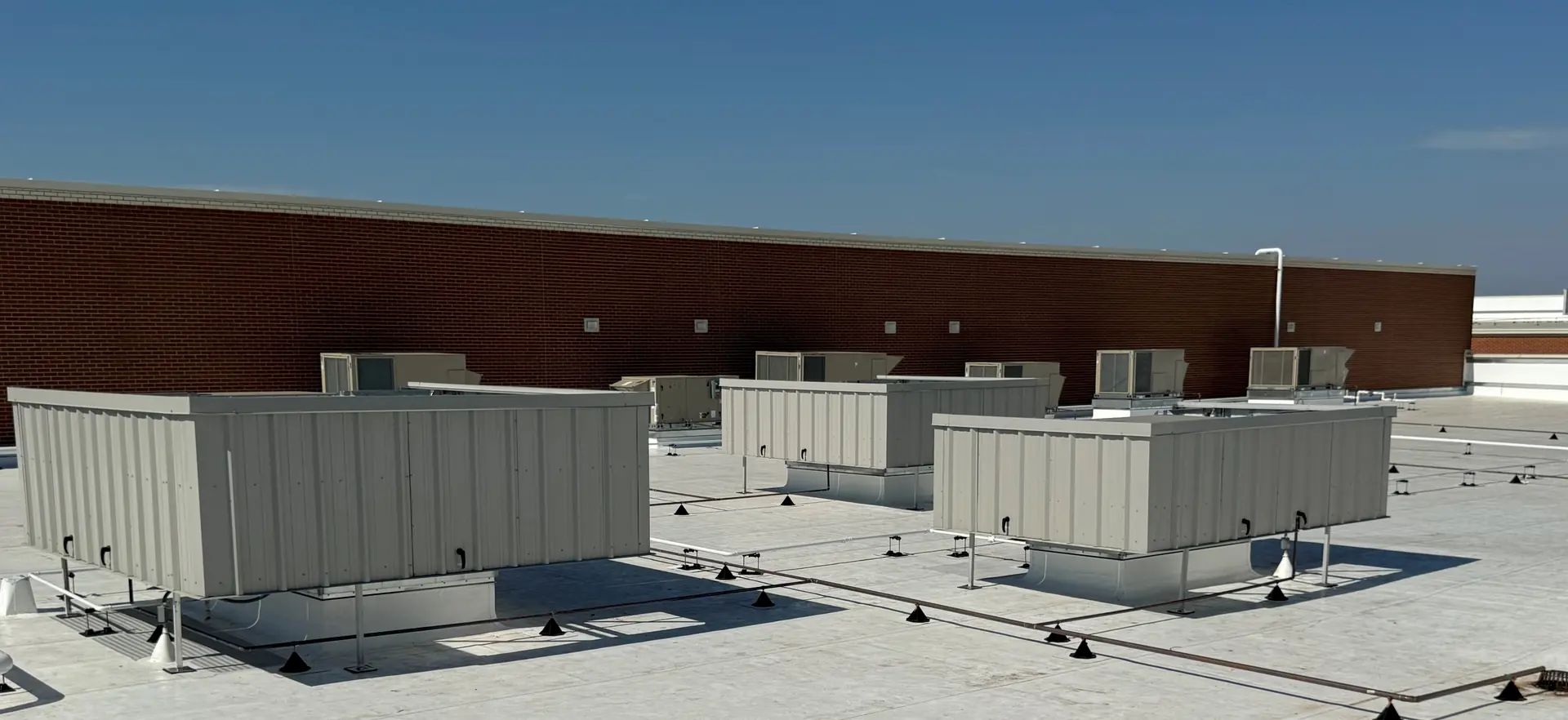 Multiple rooftop equipment screens in a row along a brick parapet wall